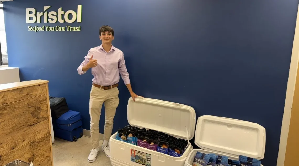 Nicholas Maruo giving thumbs up in front of Bristol Seafood signage.