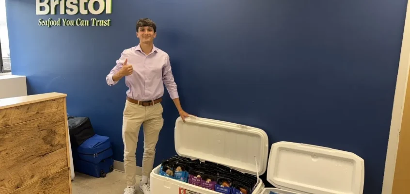 Nicholas Maruo giving thumbs up in front of Bristol Seafood signage.