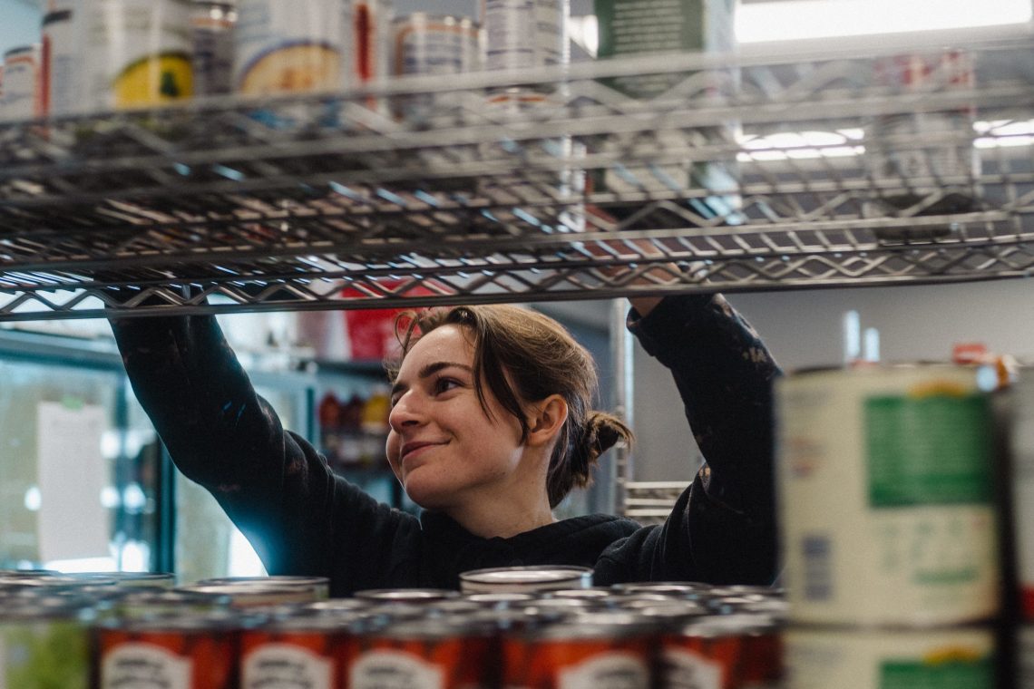 Person organizing shelves inside the Oakhurst campus food pantry at the University of Southern Maine’s Portland campus.