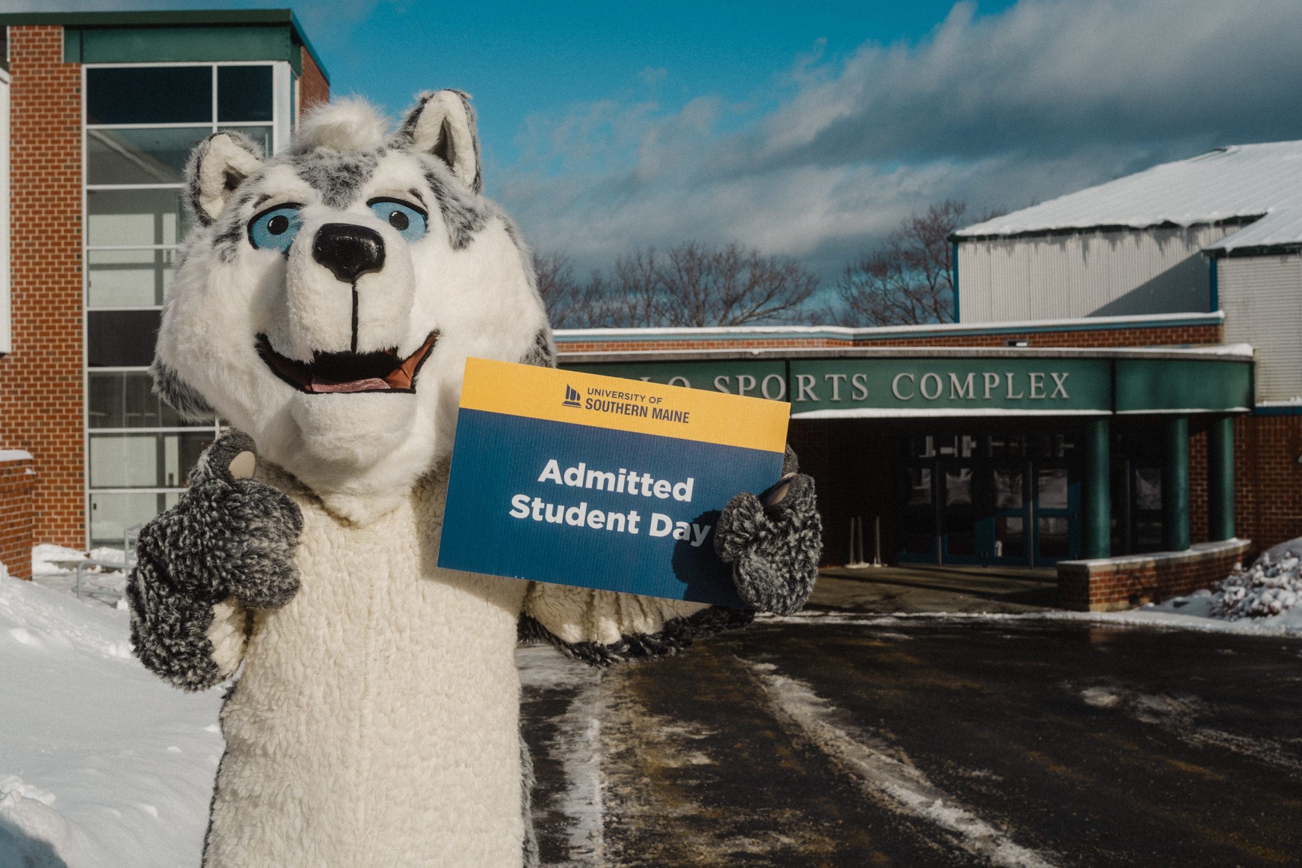 USM mascot Champ the Husky displays an Admitted Students Day sign on the Gorham campus