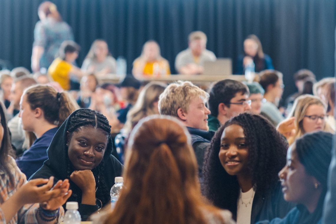 tudents engage in conversation while seated at a table on campus