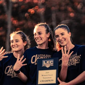 USM women’s soccer seniors smiling and holding up four fingers to celebrate their Little East Conference win.