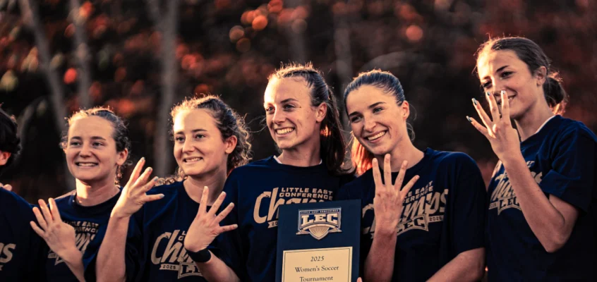 USM women’s soccer seniors smiling and holding up four fingers to celebrate their Little East Conference win.