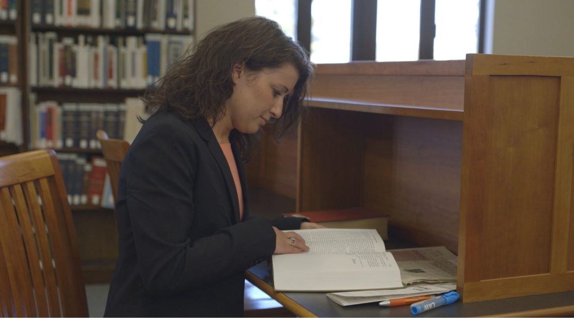 Student utilizing a textbook from the course reserves at the USM Glickman Family Library.