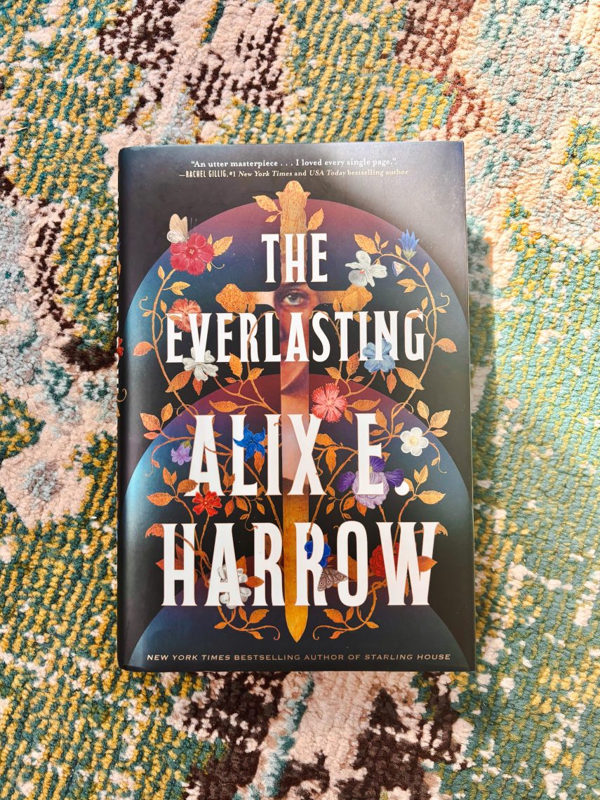 A copy of The Everlasting by Alix E. Harrow resting on a textured, colorful rug.