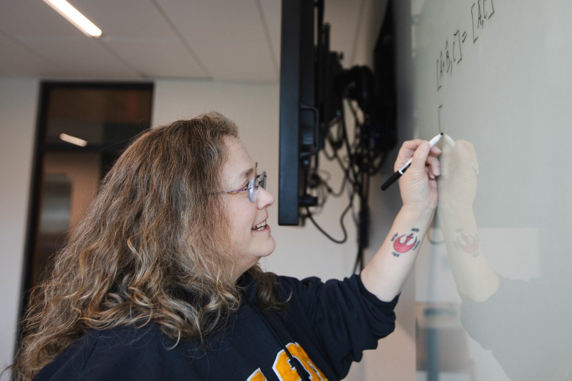 Lisa Struebing writes a physics equation on a whiteboard in the Dubyak Center on USM's Portland campus.