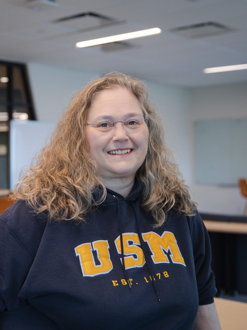 Lisa Struebing, a two-time USM graduate, smiles wearing a USM sweatshirt.