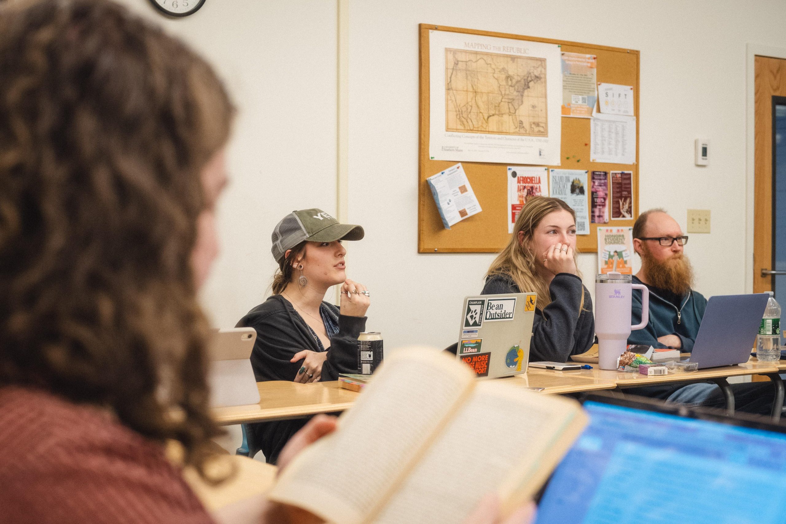 USM students engage in a class discussion with books open on their desks.