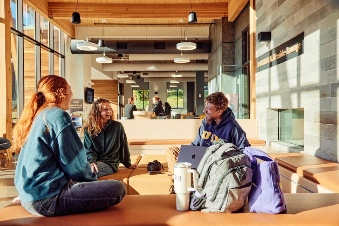 Deklin Fitzgerald laughs and chats with friends in McGoldrick Center on USM's Portland campus.