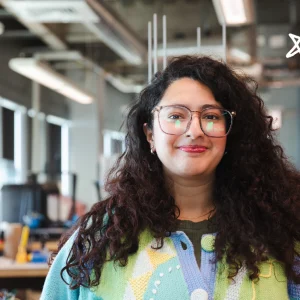 Prashiddhi Pokhrel, a graduate student and MIST Lab student employee, in the Maker Innovation Studio at USM. White star doodles overlay the image in the upper right hand corner.