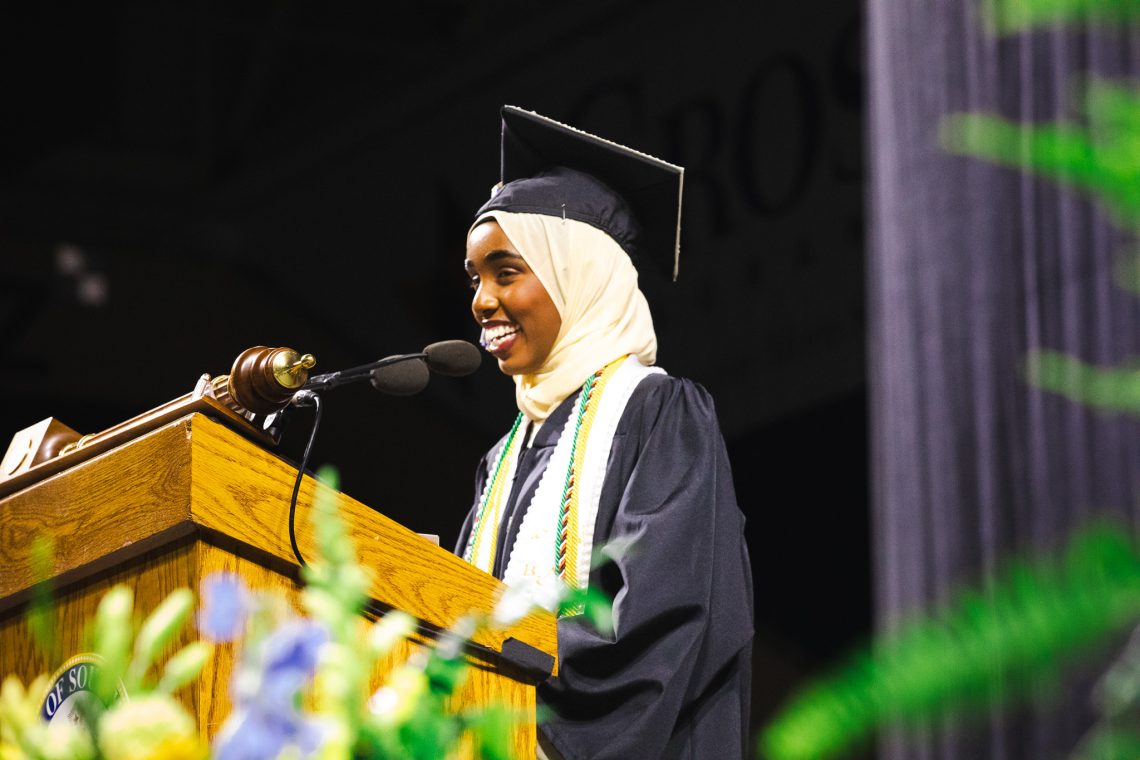 Student commencement speaker Najmo Ahmed addresses the Class of 2026 from the podium at Cross Insurance Arena.