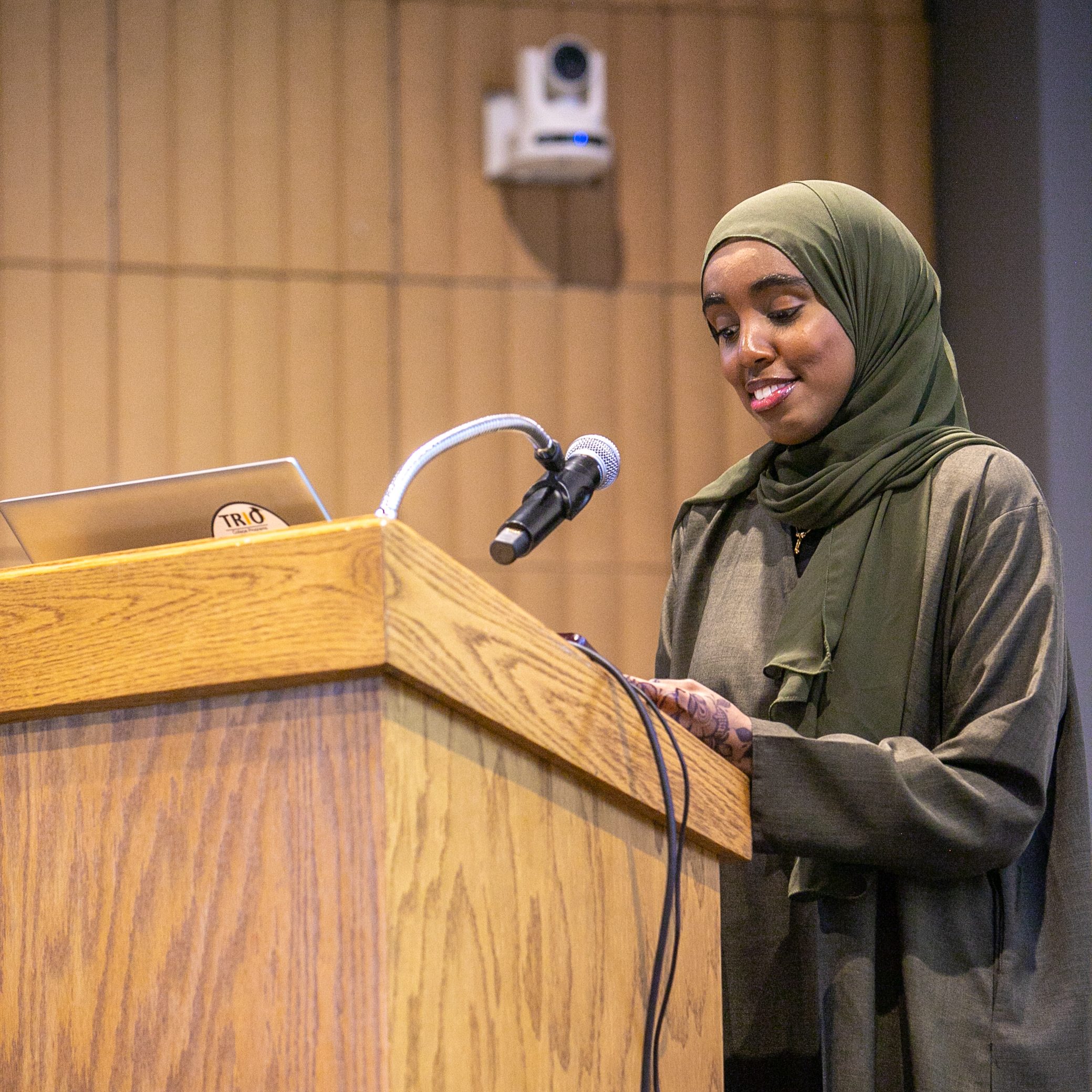 Najmo Ahmed speaks and smiles at a podium during a USM event.