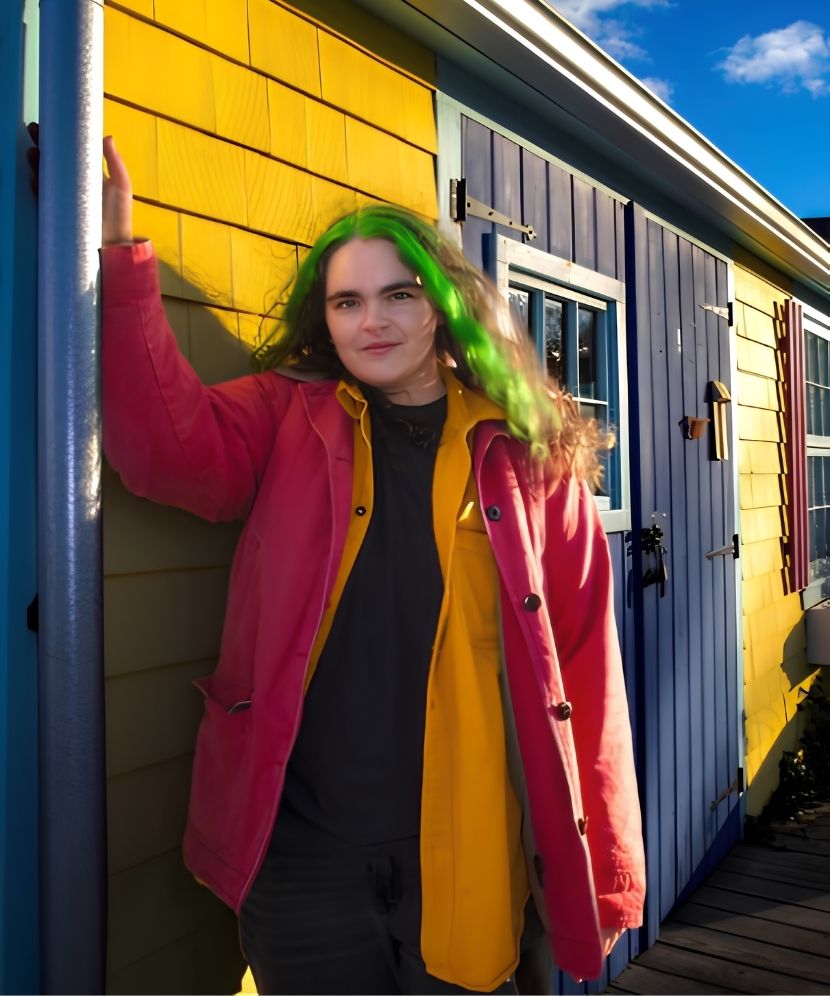 Student Ellie McGee standing outside of a yellow singled house.