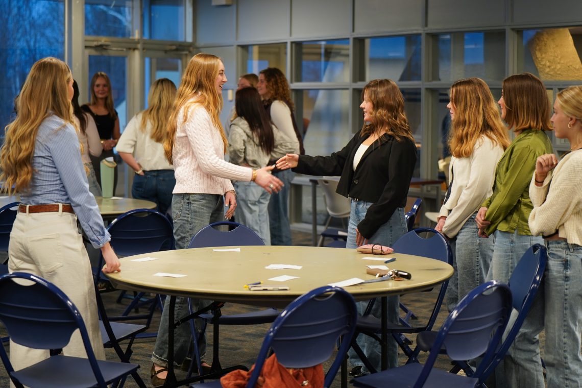 Students practice professional handshakes during a Women in Business Club networking activity at the University of Southern Maine.