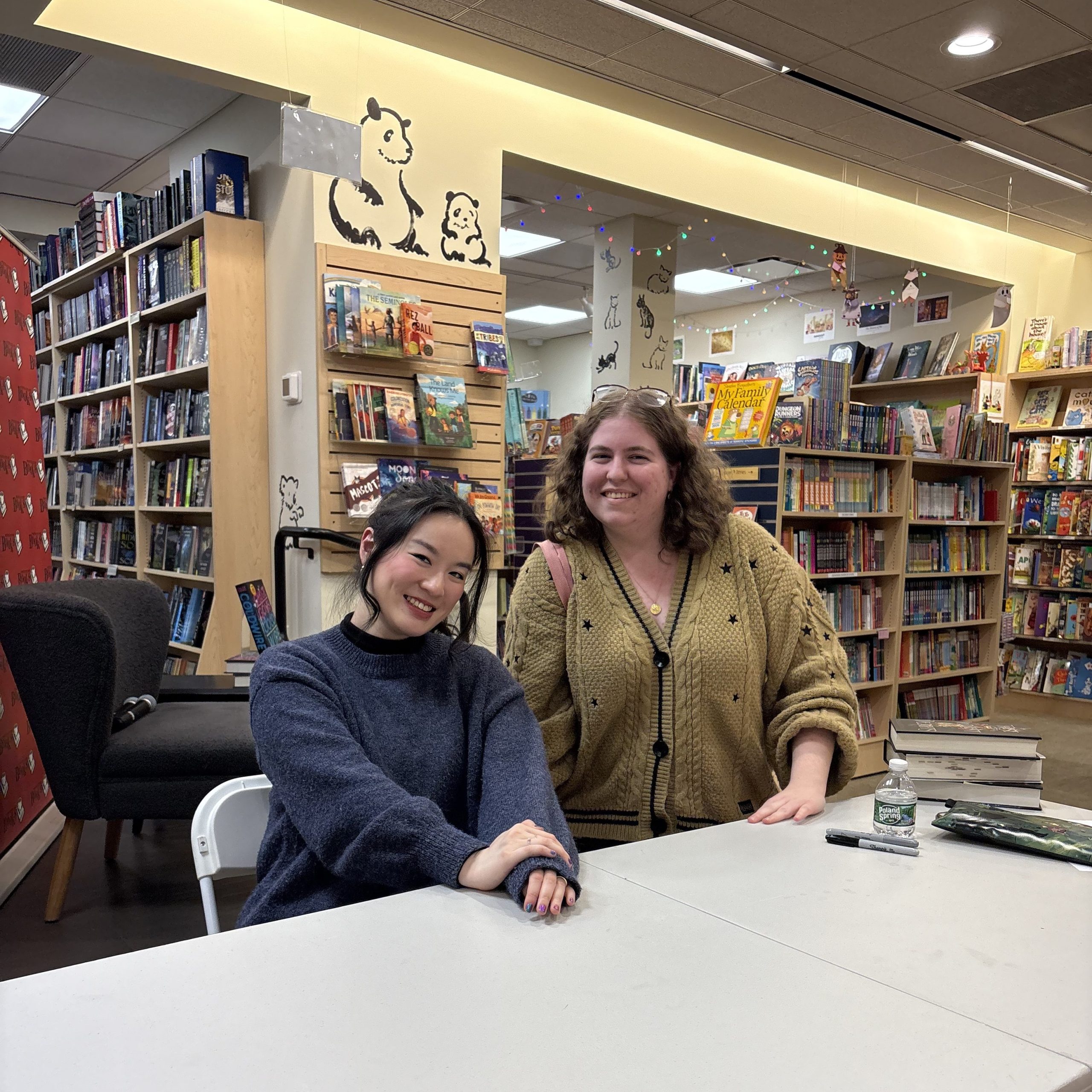 A reader stands beside author Chloe Gong at a signing table inside a bookstore, both smiling at the camera.