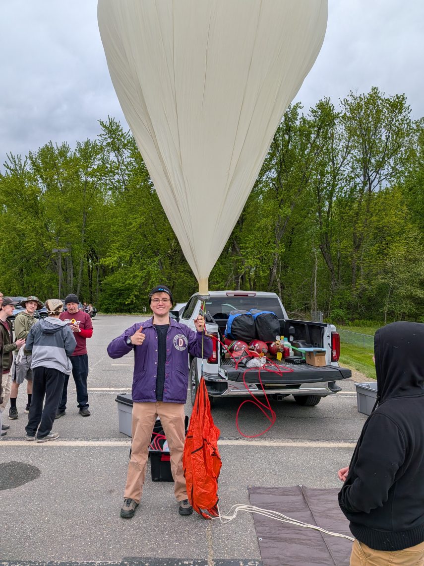 High school student holding the inflated ballon that is about to carry their cubesat to the edge of space.