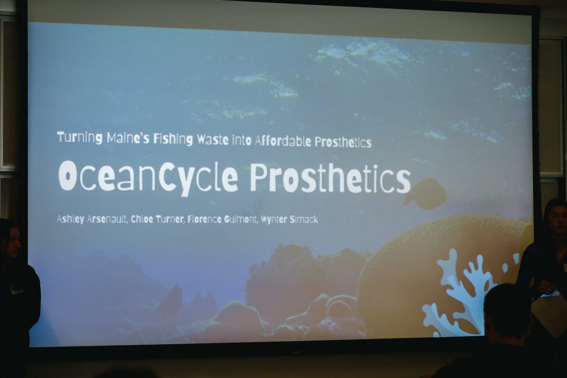 Presentation slide reading "Turning Maine's Fishing Waste into Affordable Prosthetics — OceanCycle Prosthetics" with team members' names displayed during pitch event
