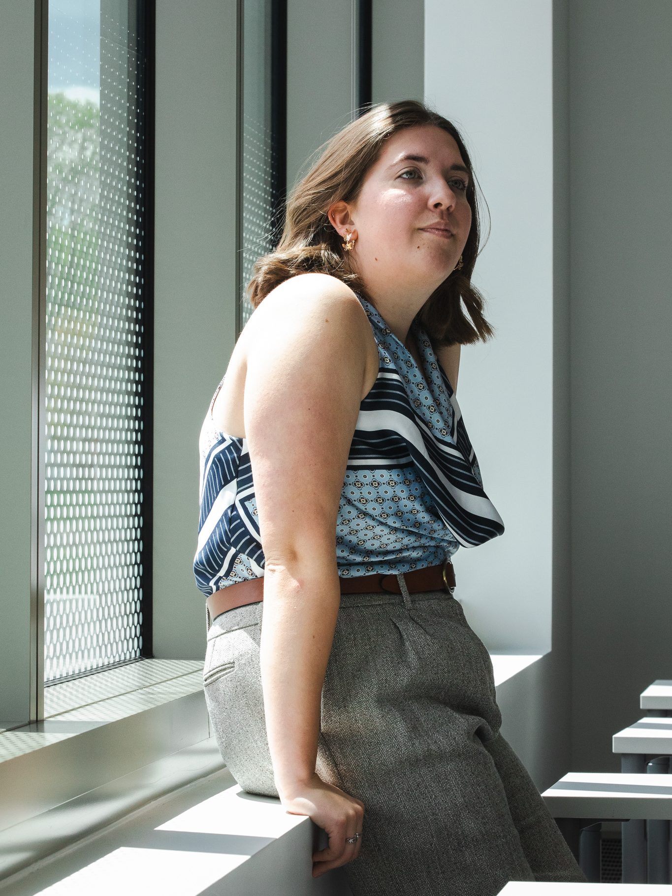 Hannah Paterson sits on a windowsill in the Crewe Center, looking out toward natural light.
