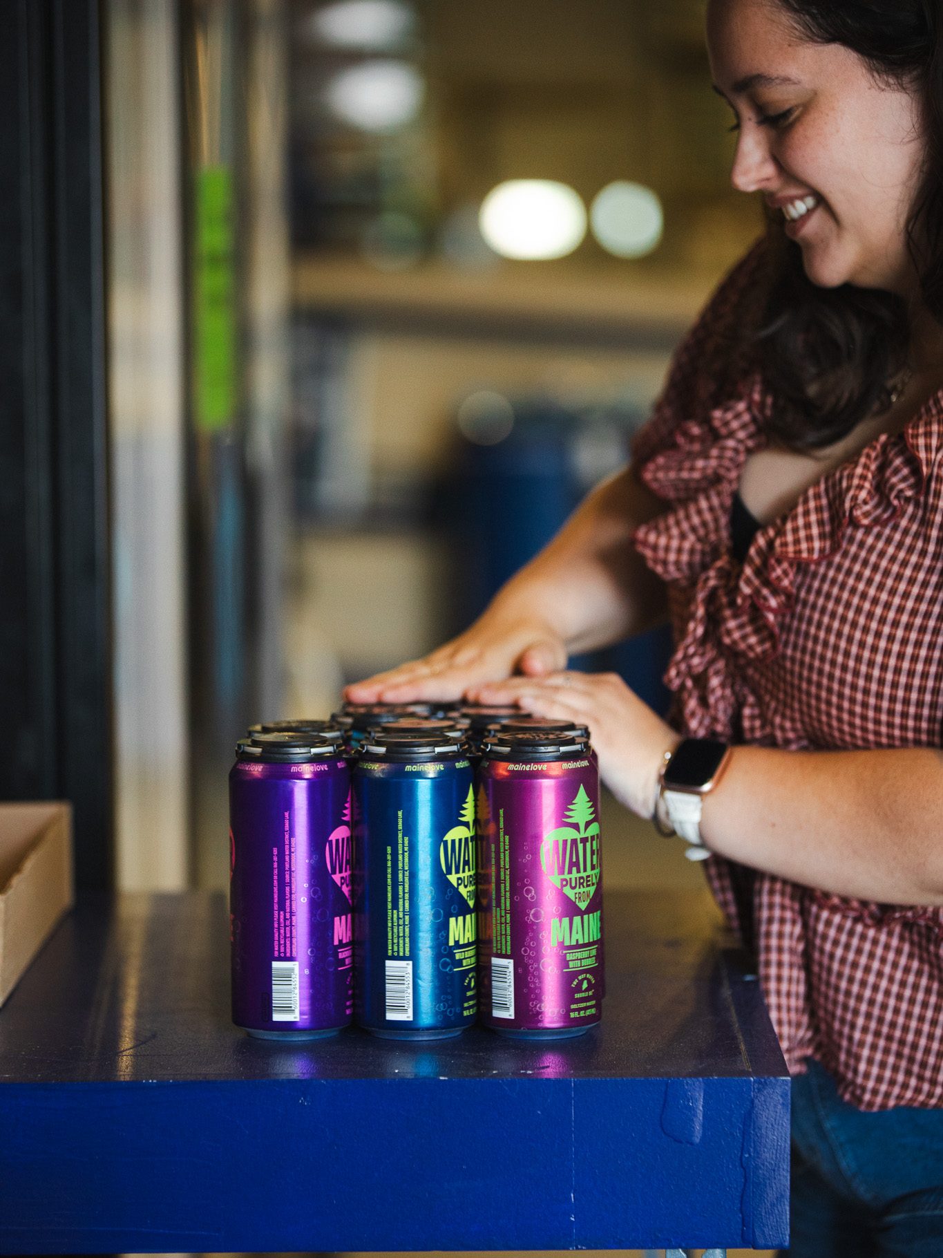 Olivia O'Donnell arranges cans of mainelove sparkling water in the warehouse at mainelove's Westbrook facility.