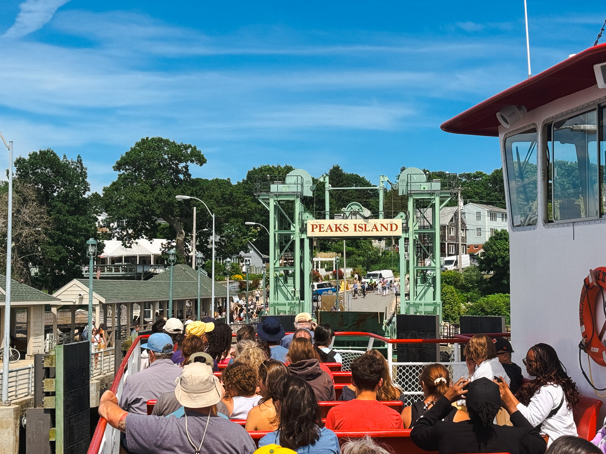 Ferry passengers arriving at the Peaks Island dock with the Peaks Island sign visible ahead, Casco Bay, Maine