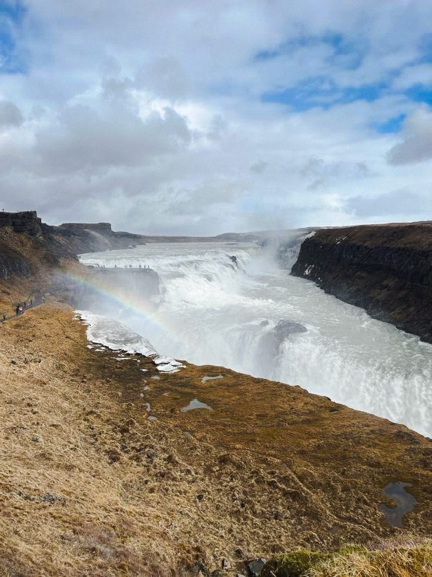 Gullfoss waterfall in Iceland with rainbow arching over rushing glacial water and canyon walls