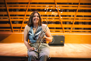Hannah Paterson smiles while holding her trumpet on the Crewe Center's stage, with illustrated music notes and an American flag floating around her.
