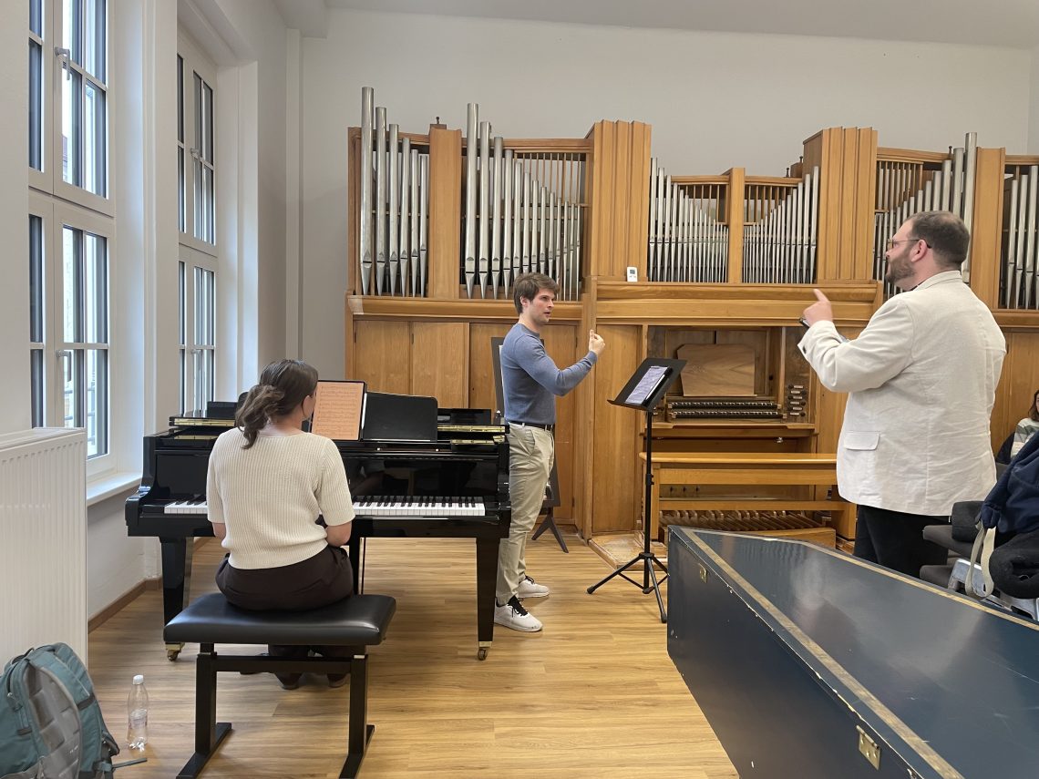 Mackenzie at the piano while Caleb gives critique of a students work.