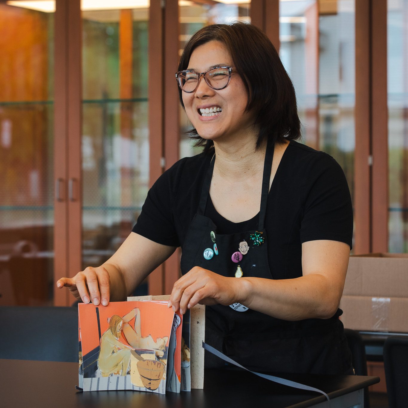 Annie Lee-Zimerle laughs while handling artist books in the Book Arts studio at the Crewe Center.