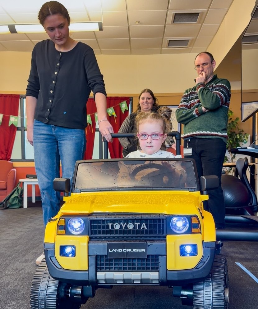 Claire in her adapted toy car with Daylin Soule and Scott Eaton assessing for any other alterations.