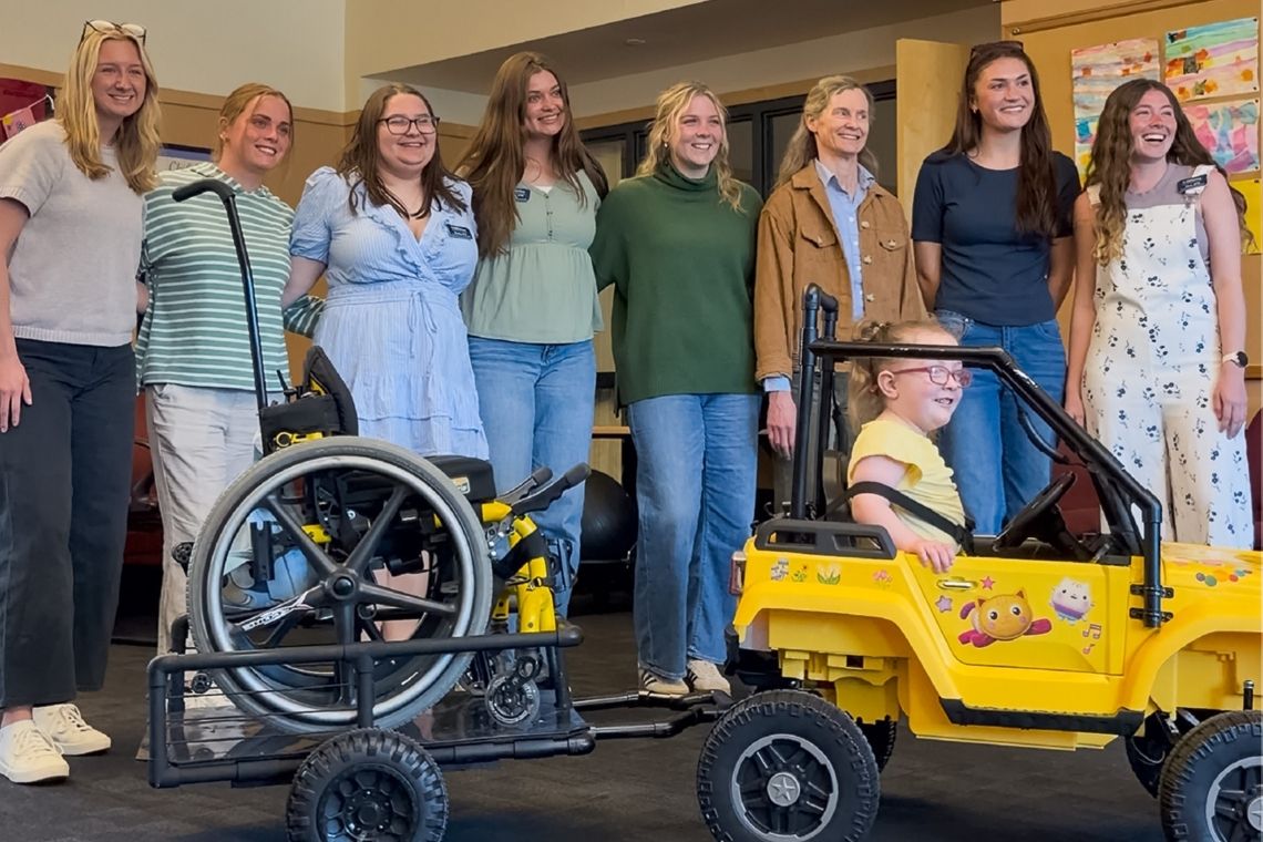 Team photo of USM Go Baby Go and Claire in her newly adapted toy car.