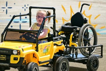 Clare driving in her newly adapted toy car created for her through Go Baby Go and USM.