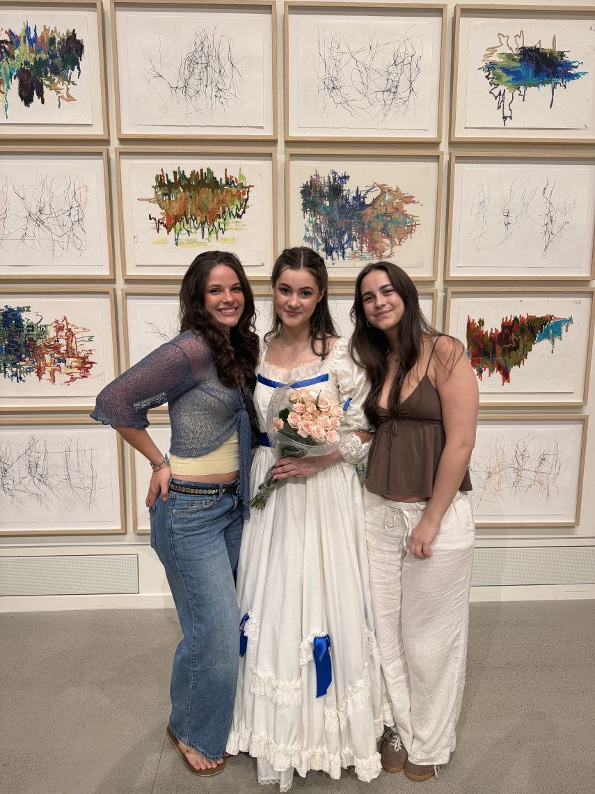 Emma and four friends crowd together for a group photo indoors, smiling at the camera.
