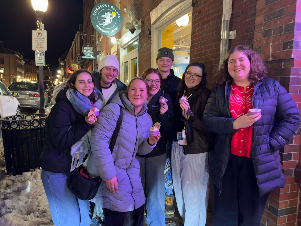 Seven smiling students hold cups of gelato outside Gorgeous Gelato on a snowy winter night in Portland.