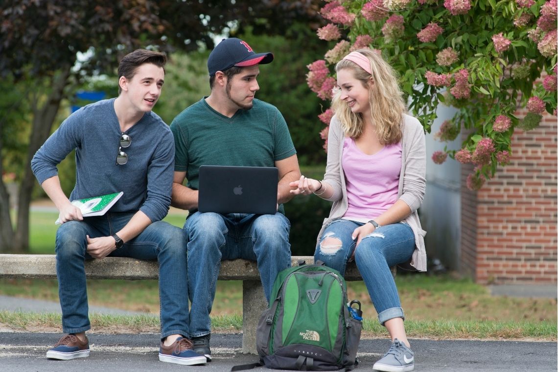 Students on campus working around a laptop.