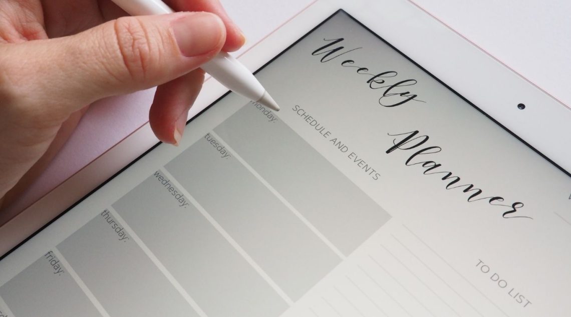 Person filling out weekly planner on an iPad.