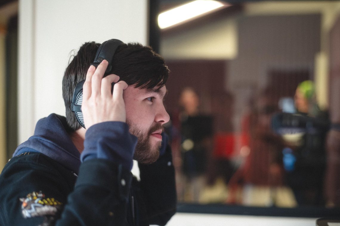 Student in profile adjusts a pair of over-ear headphones while looking ahead