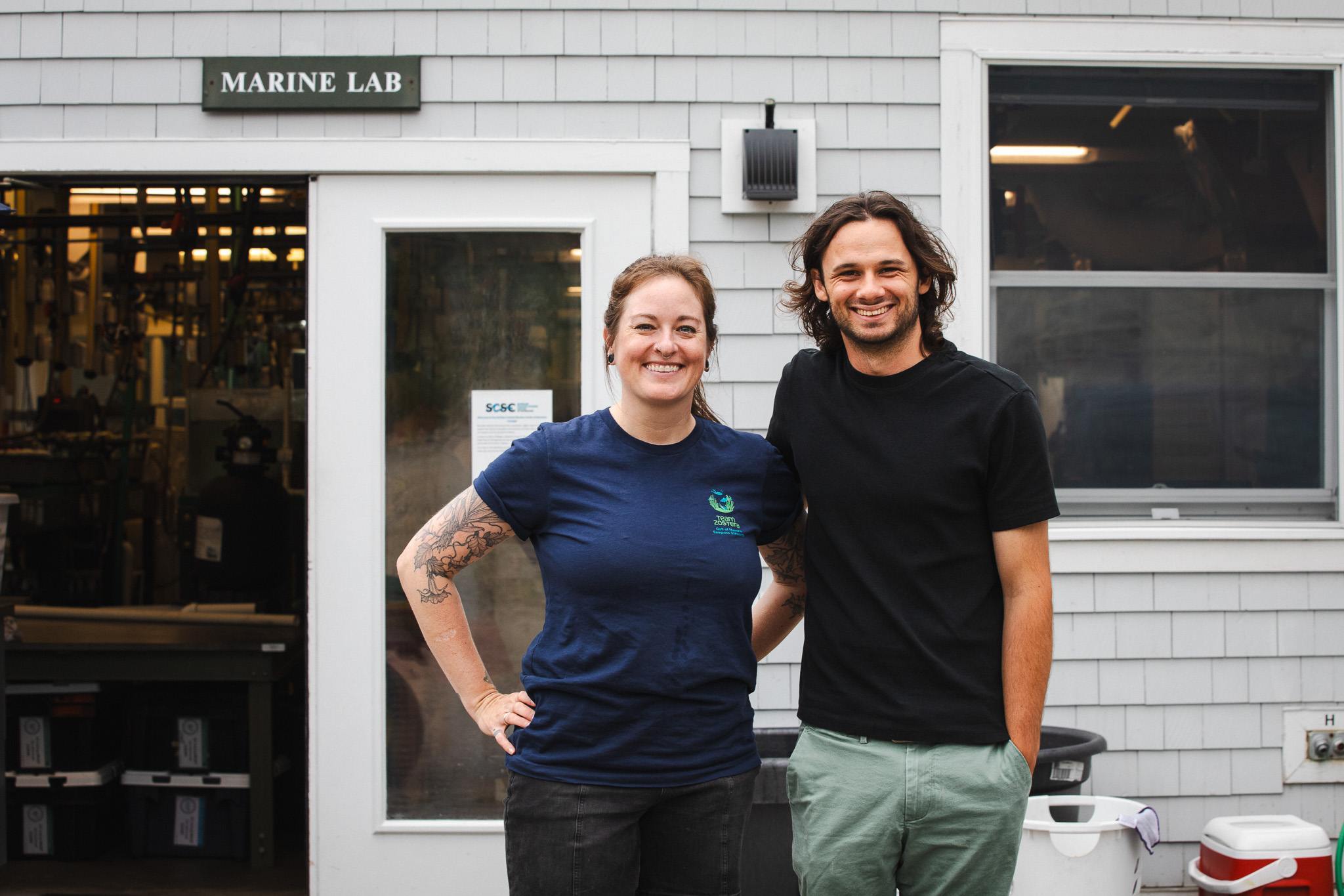 Allison Fogg and Luc Harrison smile together outside the Marine Lab building at Schiller Coastal Studies Center.