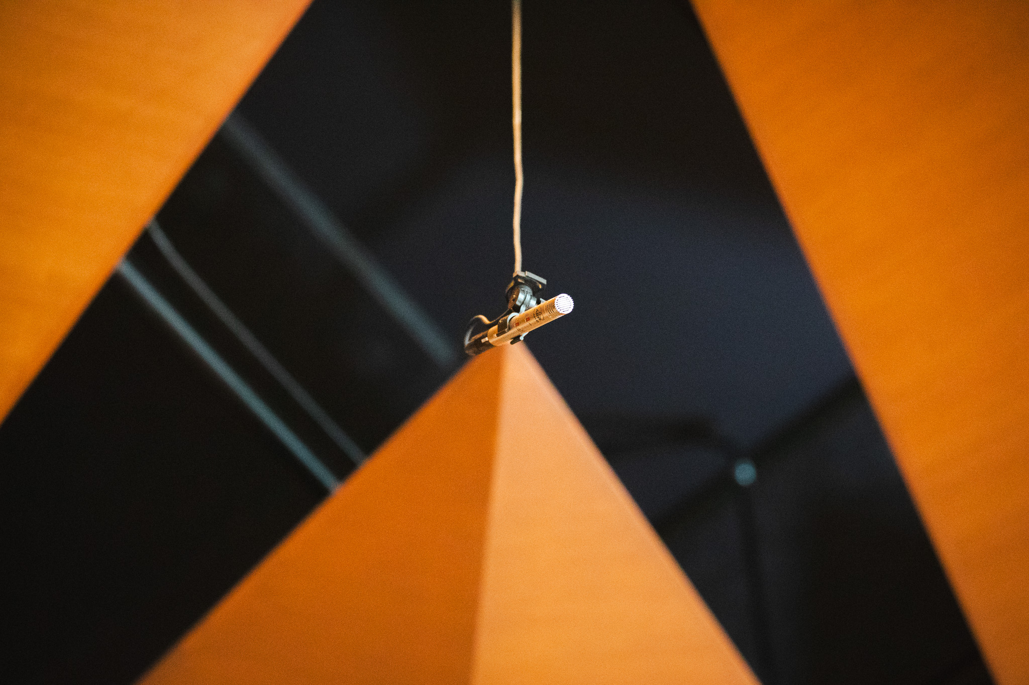 A condenser microphone hangs from the ceiling among the acoustic panels in the Crewe Center for the Arts.