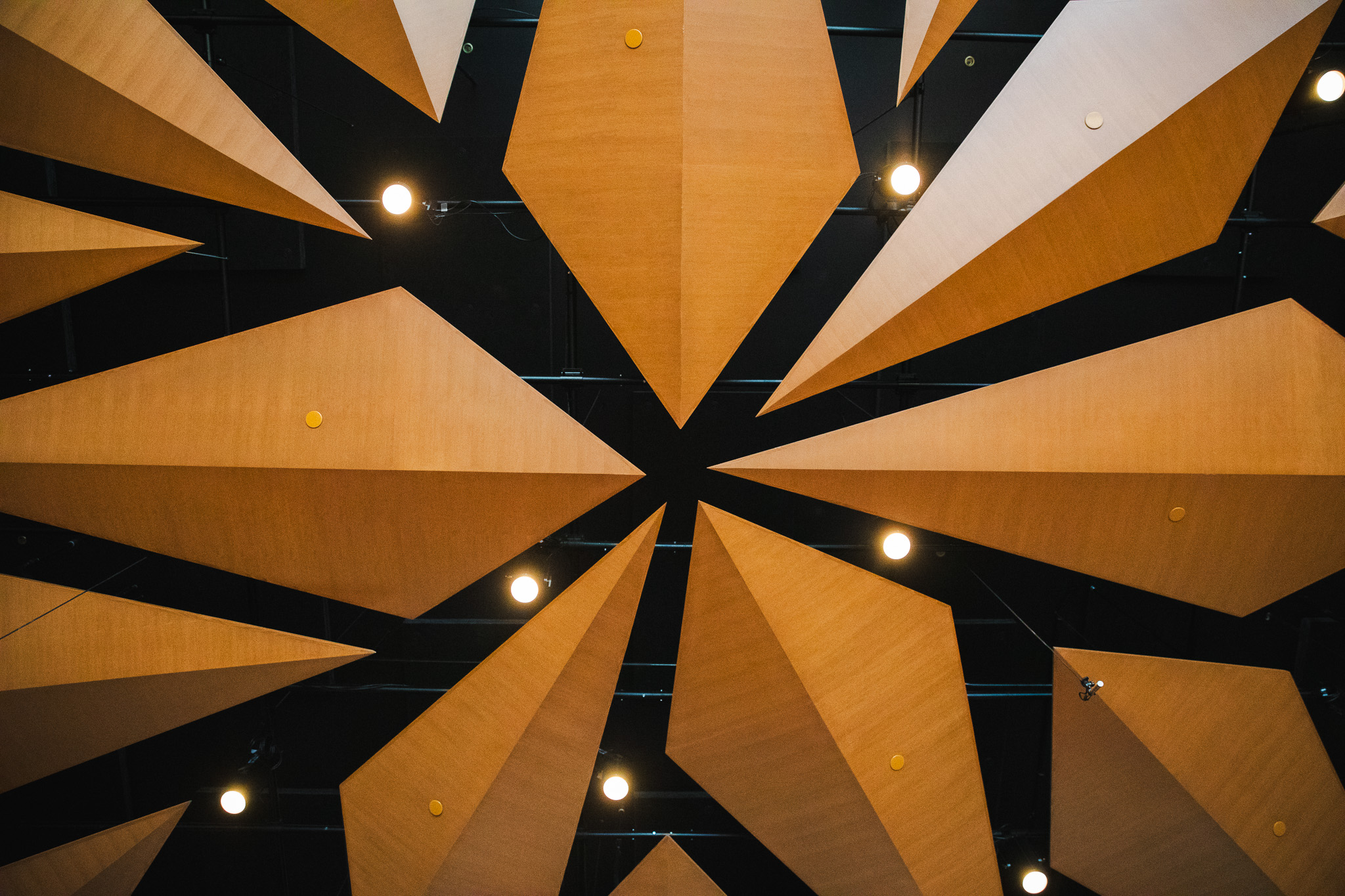 The angled wooden acoustic reflector panels on the ceiling of the Crewe Center's performance hall, viewed from below.