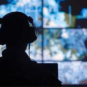 Stylistic image of a person wearing headphones watching multiple screens, mirroring CIA analyst activites.