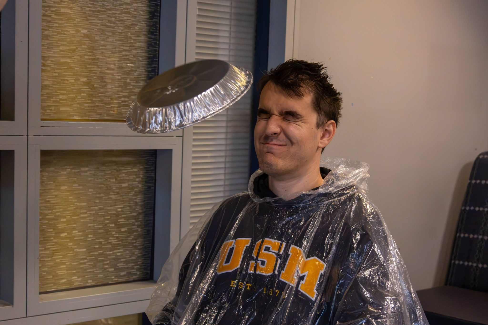 USM Student Body President Ted Campbell wearing a plastic poncho as a pie flies toward his face at Fall Fest
