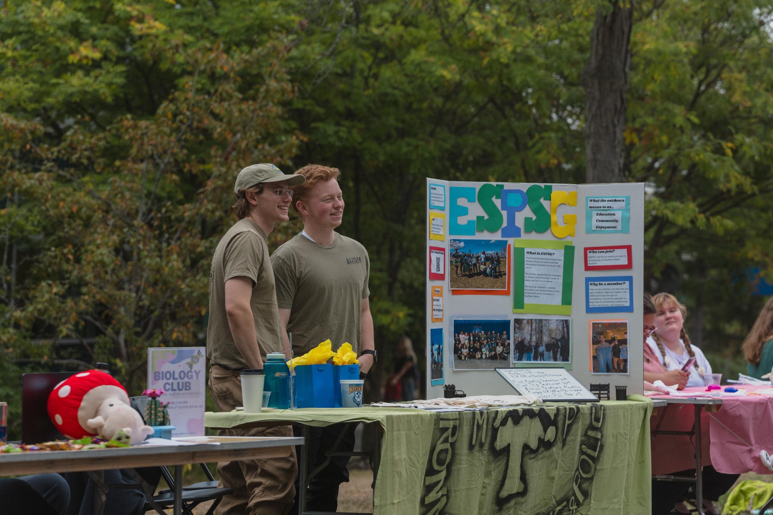 Two USM students smile while tabling for the Environmental Science and Policy Student Group at Husky Fest, USM's fall campus resource fair.