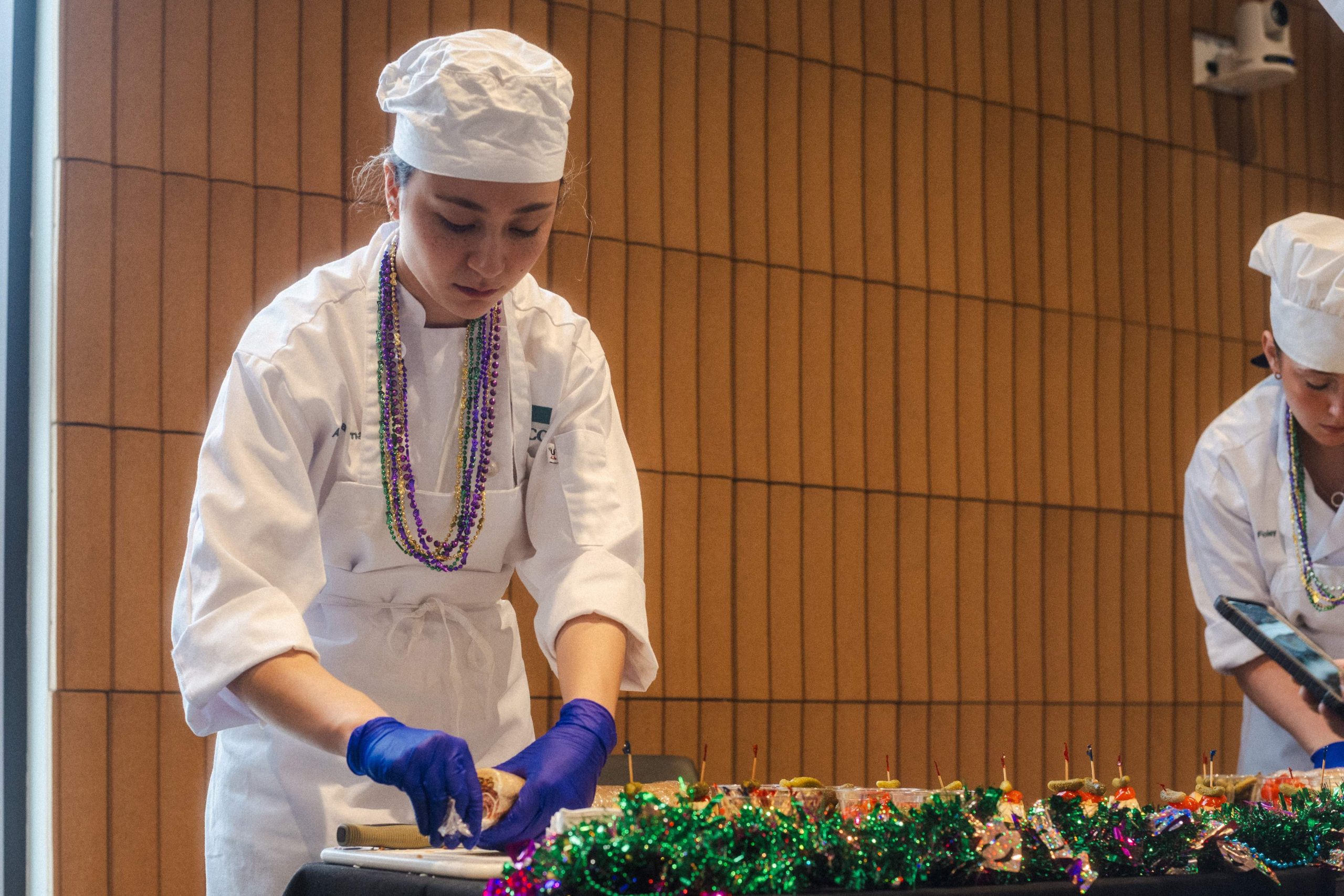 A chef in Mardi Gras beads plates Cajun-style appetizers at WMPG's Cajun Cookin' Challenge at USM.