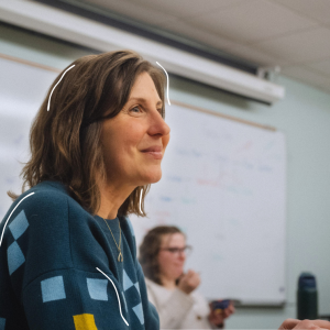 A professor smiles while engaging with students during a classroom discussion