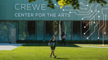 A student walks in front of the Crewe Center for the Arts on USM's Portland campus, with an illustrated circuit board graphic overlaid on the building exterior.