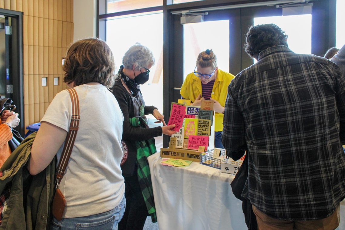 Book Bazaar attendees view art prints and handmade publications on the Pickwick Independent Press table.