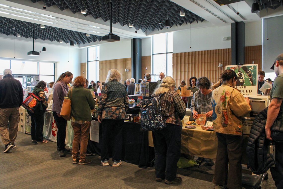 A crowd of people surround vendor tables at the 2026 Book Arts Bazaar