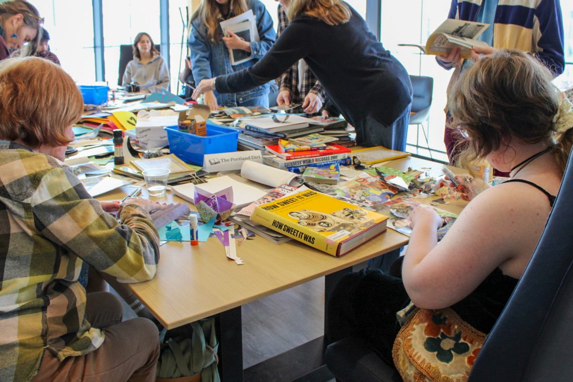 Workshop attendees actively collage paper remnants, torn books, and colorful paper into new compositions.