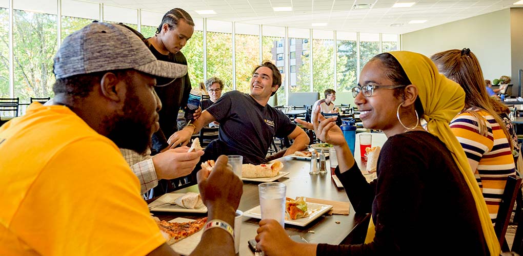 A group of students sharing a meal and lively conversation in Brooks Dining Hall on our Gorham campus.