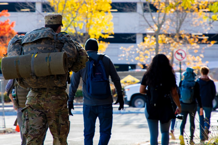 Students and staff, some in military uniform, ruck across campus
